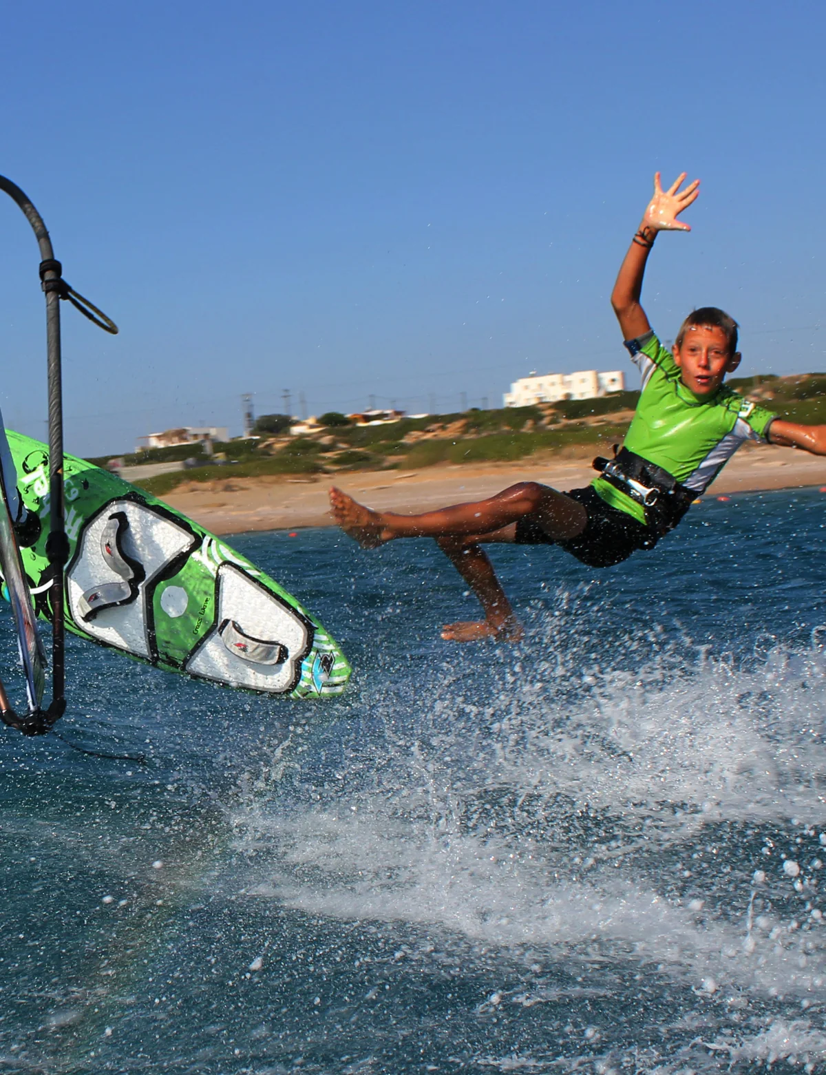 Young windsurfer with a green sail on Karpathos