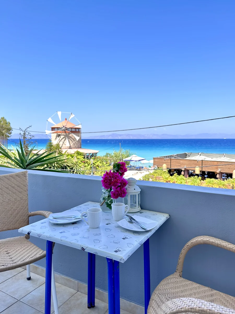 A table on the Surfhouse balcony overlooking the sea and windmill in Trianda